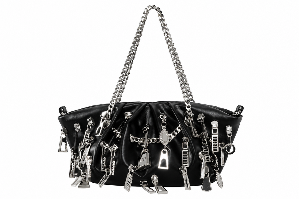 A black leather shoulder bag adorned with numerous silver zipper pulls, charms, and chain details, featuring a silver chain strap, set against a plain white background.